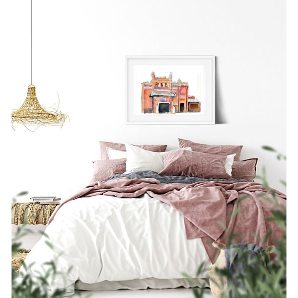 Pink and Coral Ho Chi Minh City Graphic illustration Watercolor Wall art. Atmospheric, painted illustration. Colorful visual art. Historic site graphic art against a white wall, above a bed in a white bedroom decor.  Magical realism. Timeless, archival print of original watercolor painting of illustrator and artist Patricia Jacques.
