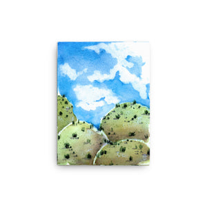12 by 16 inches blue sky stylized American Southwest blue and green Landscape watercolor canvas print. Visual art piece with bold, ethereal colors against a white wall. Print of a desert hill painting. Great for minimalist home decor. Exudes magical realism and playfulness. Emerald green grassy hills.
